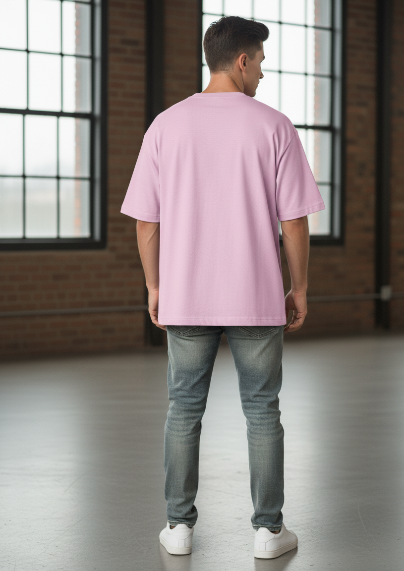 Person wearing a light baby pink t-shirt standing in a room with large windows and brick walls.
