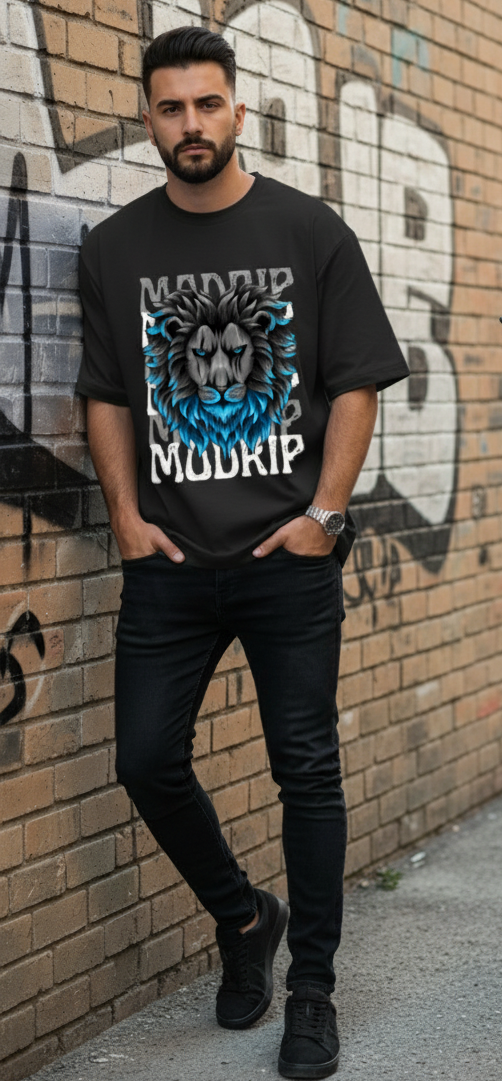 Man wearing a black t-shirt with a graphic design standing against a graffiti-covered wall.