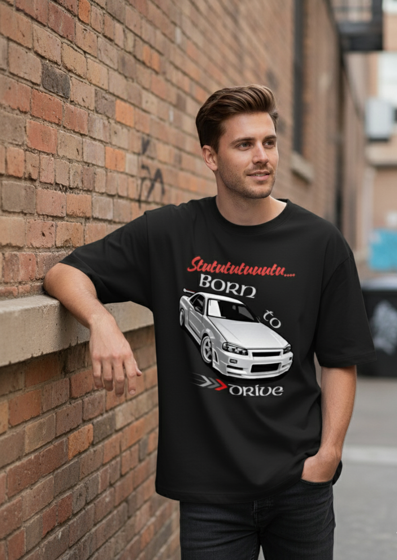 Man wearing a black t-shirt with a graphic design leaning against a brick wall.