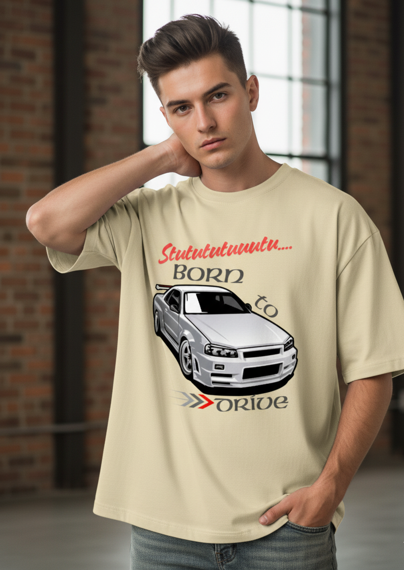 Man wearing a beige t-shirt with a car graphic and text in an urban setting