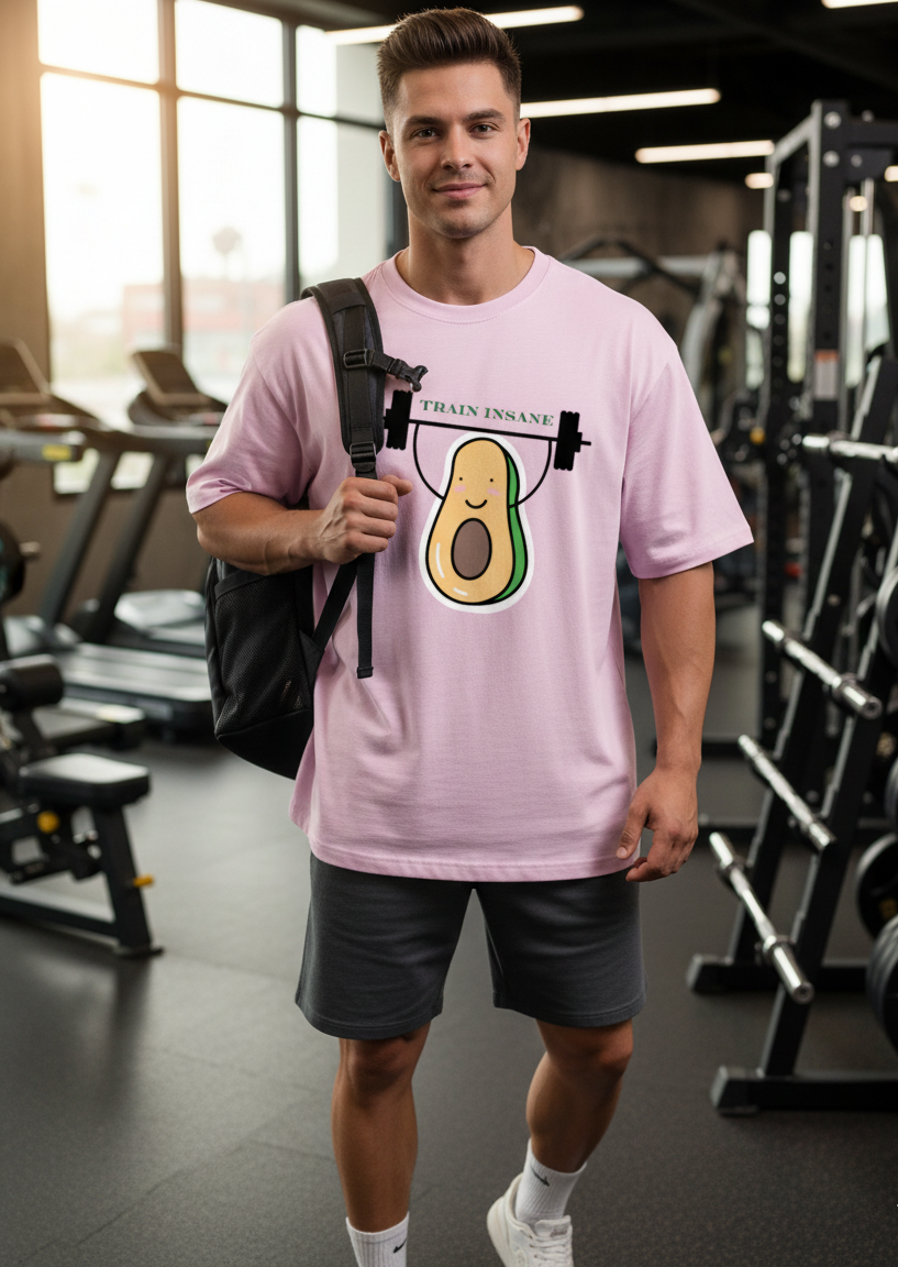 Man wearing a light baby pink t-shirt with an avocado graphic in a gym