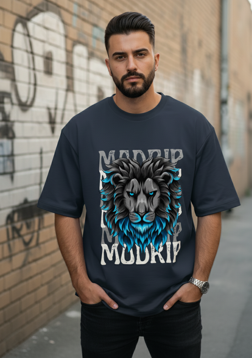 Man wearing a navy blue t-shirt with a graphic design of a lion and text, standing against a graffiti-covered wall.