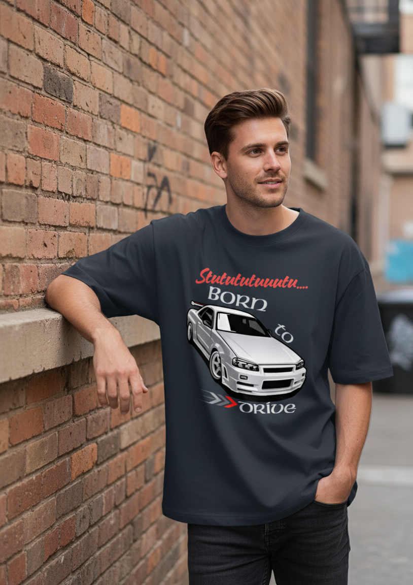 Man wearing a navy blue t-shirt with a graphic design leaning against a brick wall.