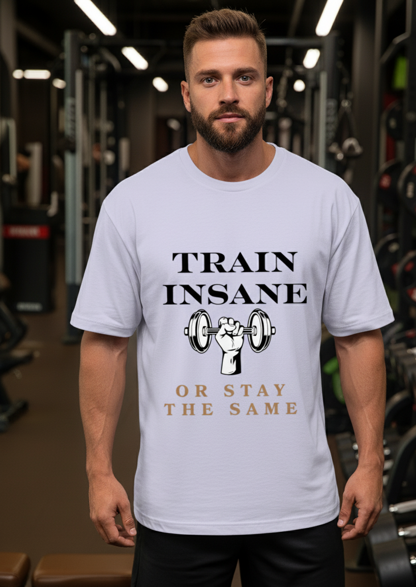 Man wearing a lavender t-shirt with 'Train Insane or Stay the Same' text in a gym setting